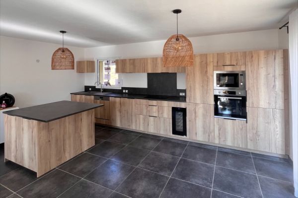 Grande cuisine ouverte en bois et noir de Mme. et M. C, une cuisine réalisée par SoCoo'c Montélimar